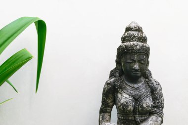 Bali, Endonezya. 6 Ekim 2018. Geleneksel Bali Adası taş heykel kadının bazı yeşil tropikal ile beyaz duvar önünde bırakır ve uzay kopyalayın
