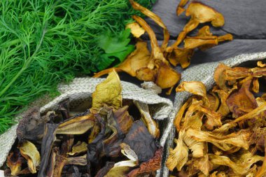 Üstten görünüm kompozisyon kuru çörek ve chanterelles mantar dereotu ve maydanoz süpürge siyah taş zemin yüzeyi ile tuval yerleştirilmiş