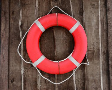 Kırmızı ve yuvarlak lifebuoy kahverengi ahşap duvarda asılı. Lifebuoy karla kaplı bir parçası