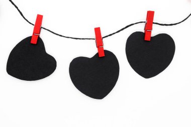 Beyaz arka plan üzerinde siyah kağıt kalpler siyah ipte asılı ve kırmızı çamaşır bağlı kopya alanı ile iğne