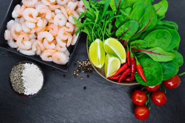 Gıda kompozisyon. Siyah kase, kara biber ve bambu kase siyah taş zemin üzerine çeşitli sebze ve deniz tuzu doğal Hindistan cevizi ağacı ahşap kase karides