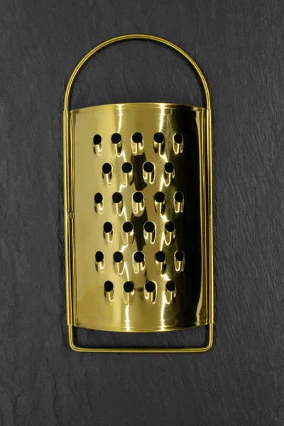 Golden grater on black stone background — Stock Photo, Image