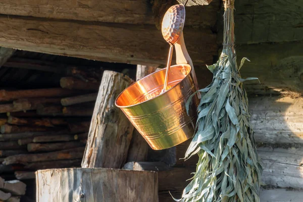Islak bakır kovanın, banyonun ve okaliptüs süpürgesinin arka planında sauna malzemesi fotokopi alanı ile ahır duvarında asılı.