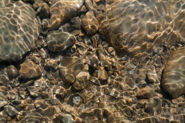 Güneş ışığının yumuşak suyun altındaki kayalara yansıdığı berrak bir dere doğal güzellikleri gözler önüne seriyor..