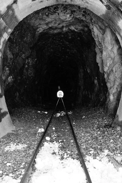 Railway tunnel with train at the end black and white. Locomotive at the end of tunnel monochrome. Transportation and road concept. Railroad travel. Rock vintage tunnel. Light at the end of tunnel.