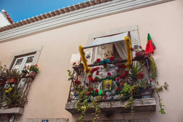 Balcony with portuguese flag and flowers in Lisbon, Portugal. Urban exterior decoration. Balconies decor concept. Traditional portuguese building facade. Travel and tourism concept. European architecture details.