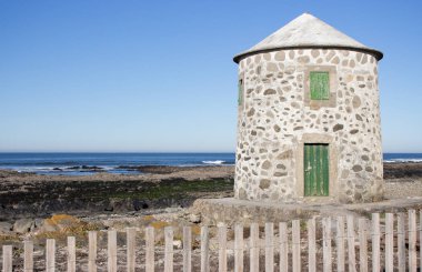 Atlantik okyanusu kıyısında kapalı yeşil kapı ve pencereler ile terk edilmiş eski deniz feneri, Portekiz. Ahşap çitin arkasında deniz feneri. Ortaçağ mimarisi. Camino de Santiago üzerinde Manzara. Sahilde antik deniz feneri.