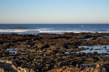 Avrupa'da Atlantik Okyanusu'nun doğal manzarası. Okyanusun kayalık sahili. Deniz kıyısında sabah. Yaz tatili ve turizm. Kayalar ve dalgalar ile güzel kıyı şeridi.