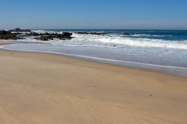 Dalgalar Atlantik Okyanusu sahilinde kayalara çarpıyor. Doğal deniz manzarası. Deniz kenarında güzel sörf. Köpük ile sıçrama dalgaları. Sahilde seyahat ve tatil. Kayalık sahil şeridi. Doğa gücü.