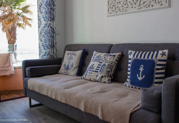 Kanepe ve yastıklı konforlu bir oda. Mavi renklerde rahat daire iç. Şık dekor ve mobilyaile oturma odası. Çapalı yastıklar. Okyanus villa odası. Tatil ve dinlenme konsepti.