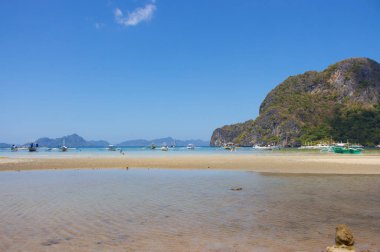 Filipinler'de deniz kıyısında geleneksel Filipinler tekneler. Ufukta adalar ve dağlar ile doğal tropikal manzara. Yaz tatili ve seyahat. Asya'da pastoral lagün. Güneşli günde tropikal cennet. 