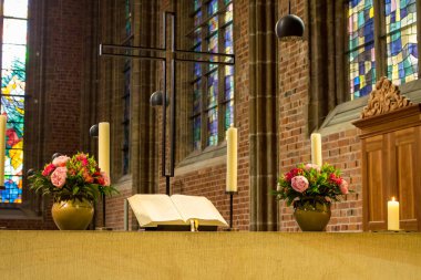 Katolik Katedrali'nde güzel sunak. Çiçekler, mumlar ve haç ile Kutsal Kitap açın. Din ve inanç kavramı. Kilisenin zarif dekorasyonu. Kütle selaatları. Şapelin içi. Dini semboller. 