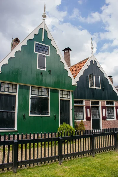 Facade of traditional dutch buildings in village. Brick and wooden houses in Zaanse Schans, Netherlands. Typical North Holland architecture. Rural buildings with garden and porch. Calm countryside view.