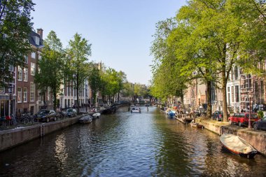 Amsterdam, Hollanda-06/14/2019: Amsterdam, Hollanda 'da köprü ve tekneler ile kanal. Geleneksel Hollanda şehir manzarası. Tekneler ve turistler ile Amsterdam 'da tarihi sokak. Yaz seyahat konsepti.