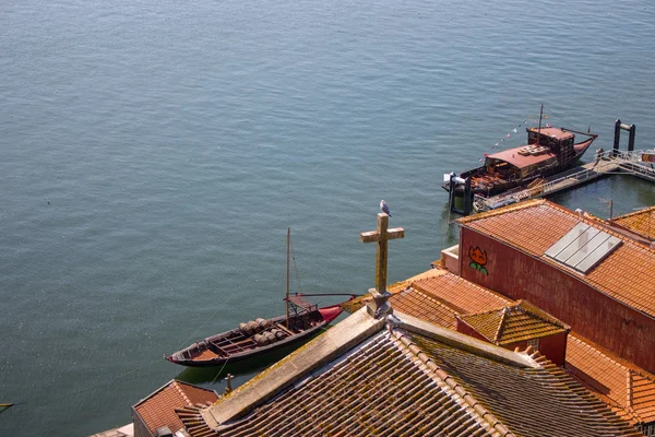 Red roofs with cross on river Douro background top view. Embankment with church roof and wooden cross in Porto, Portugal. Portuguese landscape. Summer travel. River harbour top view.