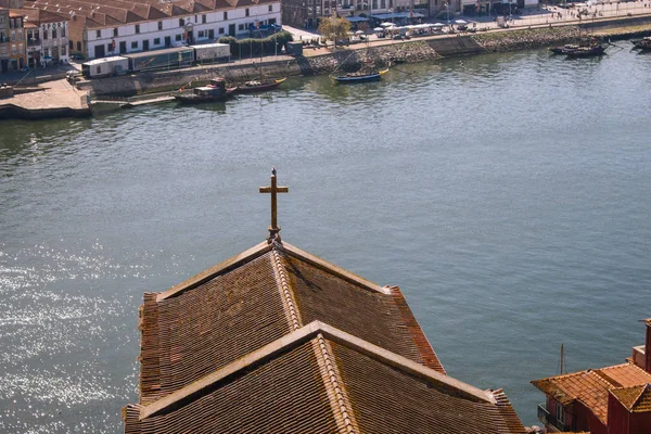 Red roofs with cross on river Douro background top view. Embankment with church roof and wooden cross in Porto, Portugal. Portuguese landscape. Summer travel. River harbour top view.