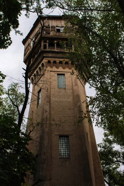 Ormanda terk edilmiş bir kule. Eski ahşap ve tuğla bina. Vintage mimari. Isınma kavramı. Ahşap balkonlu retro ev. Yıkık yüksek kulenin cephesi.