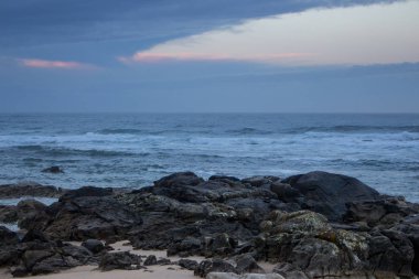 Sabah Portekiz'de Atlantik Okyanusu sahili. Mavi sabah sisinde deniz manzarası. Taşlar ve dalgalarla okyanus plajı. Boş plaj. Kayalık sahil şeridi. Sakin okyanus kıyısı. Vahşi doğa kavramı. 