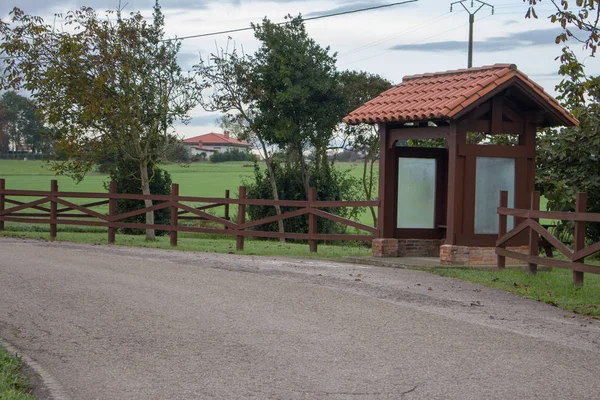 Köydeki ahşap otobüs durağı. Yol boyunca çitleri ve ağaçları olan boş kırsal otobüs durağı. Seyahat ve varış konsepti. Ulaşım konsepti. Şehir dışı seyahati. Seyahat geçmişi. Köyde dur noktası.. 