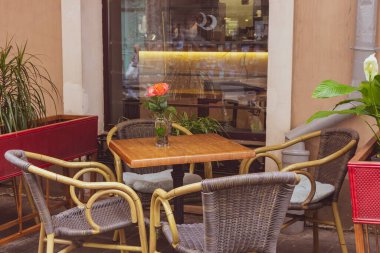 Karantina sırasında boş bir kafeterya. Masaları ve sandalyeleri olan restoran terası. Sokak kafesinin masasında çiçek var. Zarif bir sokak kafesi. Açık büfe mobilyalar. Samimi veranda arkaplanı.