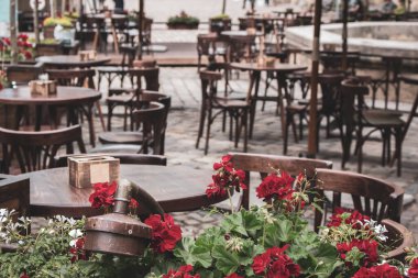 Karantina sırasında boş bir kafeterya, filtrelenmiş. Masaları ve sandalyeleri olan restoran terası, tonlu görüntü. Çiçekli sokak kafesi. Zarif bir sokak kafesi. Açık büfe mobilyalar. Samimi veranda arkaplanı.