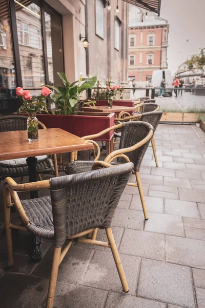 Empty outdoor cafe during quarantine. Restaurant terrace with tables and chairs. Flower on table of street cafe. Elegant street cafe. Outdoor bistro furniture. Cozy patio background.