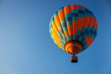 Açık mavi gökyüzünde sıcak hava balonu. Sepet kaldırma ile renkli balon. Uçak konsepti. Yaz macerası ve boş zaman. Havacılık sporu konsepti. Sakin bir sabahta parlak turuncu balon. Uçuş konsepti.