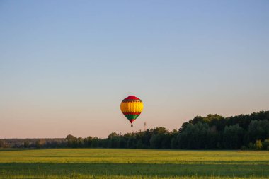 Kyiv, Ukrayna - 06 / 26 / 2020: Ağaçların üzerinde açık yaz gökyüzünde sıcak hava balonu. Yaz manzarası arka planında renkli balon. Yaz tatili. Sıcak hava balonu sabah uçuyor..