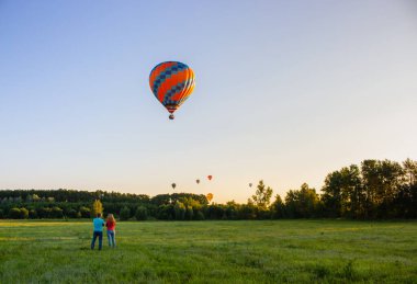 Kyiv, Ukrayna - 06 / 26 / 2020: İnsanlarla açık havada sıcak hava balonları. Hava manzaralı arka planda renkli balonlar. Yaz tatili. Sabahları sıcak hava balonu uçuyor. Balon festivali konsepti.