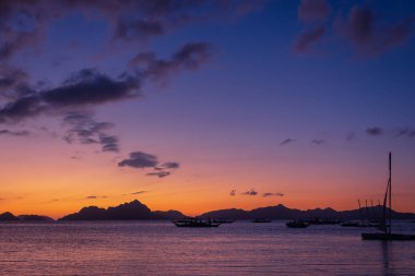 Filipinler, Palawan 'da denizin üstünde mor gün batımı. Akşam karanlığında ada ve tekne siluetleri. Asya 'da sakin bir altın akşam. Seyahat ve egzotik tatil konsepti. Tropikal manzara ve doğa. 