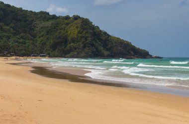 Güneşli bir günde sörfçülerle tropik bir plaj. Filipinler, Palawan 'da Duli sörf plajı. Arkasında yeşil dağ olan geniş bir sahil. Tropik bir manzara. Gök mavisi göldeki gök mavisi su. Cennet doğası. Etkin yeniden yaratma.