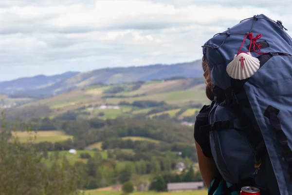 Dağ arka planında hacı kabuğu olan büyük bir sırt çantası. Hac konsepti. Camino de Santiago yolunda seyyah. Arka planda sırt çantalı bir turist. Dini seyahat. Dağlarda gezgin. 