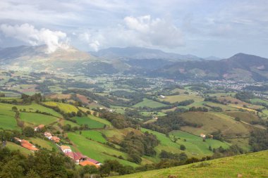 Dağ vadisindeki köy ve yol. Pireneler, İHA 'nın görüntüsü. Camino de Santiago manzarası. Hill Valley 'deki manzaralı çayırlar ve tarım arazileri. Fransa 'nın kırsalında. Seyahat ve macera.