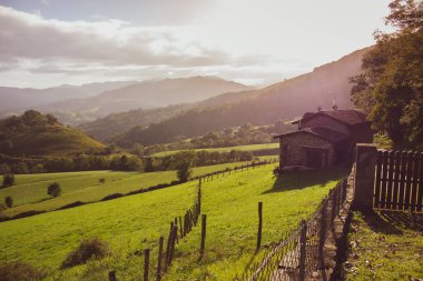 Evleri ve çitleri olan dağlar vadisi. Pireneler sonbahar manzarası. Tepe vadisindeki manzaralı çayırlar ve tarım arazileri. Fransa 'nın kırsalında. Seyahat ve macera. Dağlarda yol. Doğada güzellik.