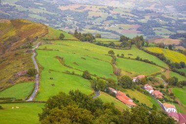 Dağ vadisindeki köy ve yol. Pireneler, İHA 'nın görüntüsü. Camino de Santiago manzarası. Hill Valley 'deki manzaralı çayırlar ve tarım arazileri. Fransa 'nın kırsalında. Seyahat ve macera.