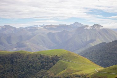 Manzaralı bulutlu dağlar vadisi. Pireneler sonbahar manzarası. Tepe vadisindeki manzaralı çayırlar ve tarım arazileri. Fransa 'nın kırsalında. Seyahat ve macera. Dağlarda yol.