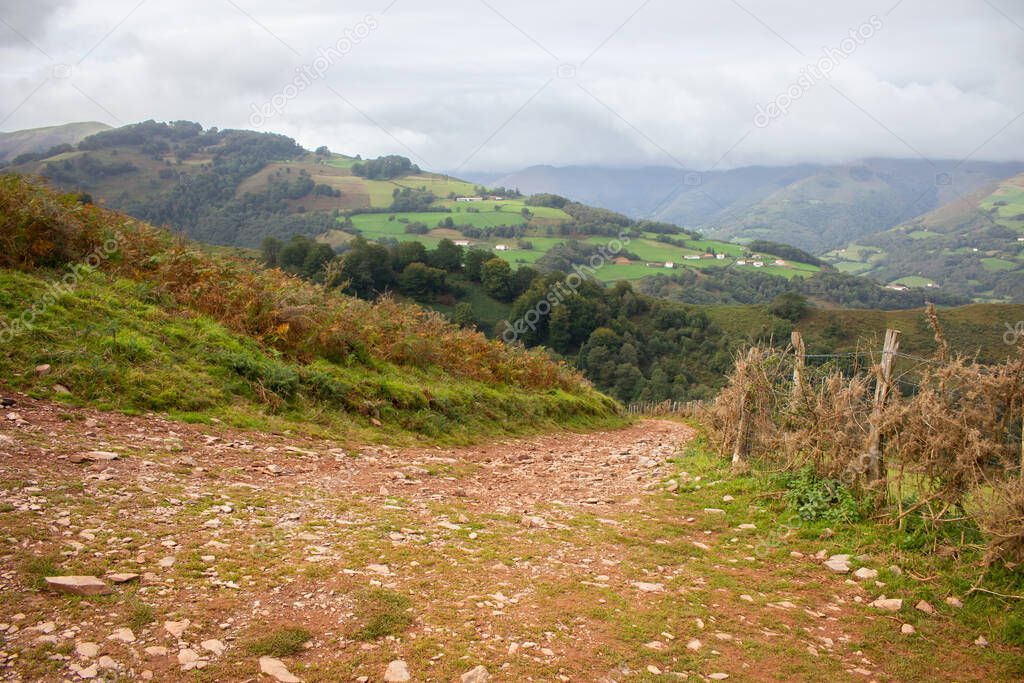 Empty path in mountains. Pyrenees autumn landscape. Scenic landscape with country road and hills valley. Countryside in France. Travel and adventure. Camino de Santiago landscape. Beauty in nature.