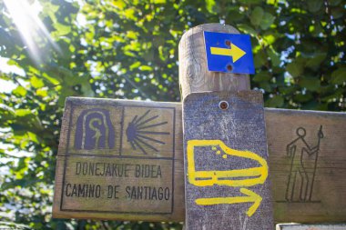 İspanya - 10 / 11 / 2019: Camino de Santiago imzalı sarı ok. Mesafeli ahşap tahta ve kelime Camino de Santiago. Hac konsepti. Dini yol işareti. Ormandaki hac sembolü. Seyahat hedefleri kavramı.