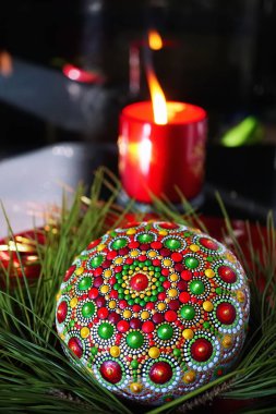 Güzel mandala bir taş kırmızı mum ve Noel ağacı dalları ile boyanmış