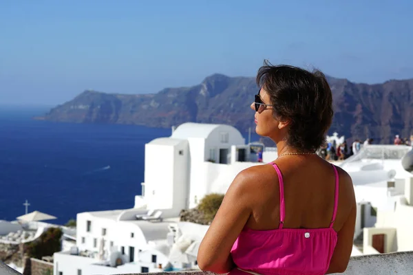 Woman with Fuchsia dress admires the Oia Scenery in Santorini, Greece