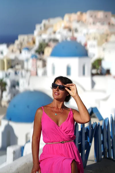 Woman with Fuchsia dress admires the Oia Scenery in Santorini, Greece