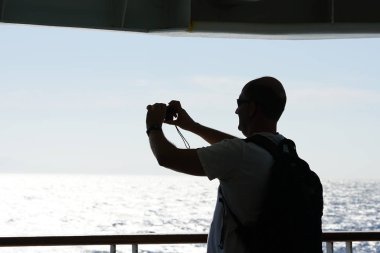 Ios, Yunanistan, 18 Eylül 2018, Bir turist Kiklad Adaları'ndaki deniz ve kayalıkların tipik manzarasını fotoğrafla