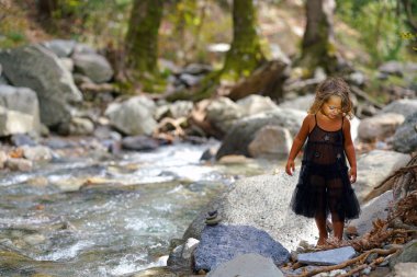 Eubeoa 'daki Dirfi Dağı' nın güzel doğasında, nehrin kenarında eski bir bebekle oynayan üç yaşındaki bir kız.