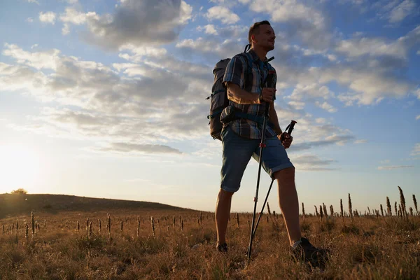 Hike mountain man hiking travel with backpack and trekking poles walking at adventure and sunset.