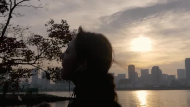 Frau Joggt Während Die Sonne Hinter Der Stadt Aufgeht — Stockvideo