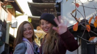 gülümseyen ve fotoğraf makinesi ile büyük Kyoto Tapınağı arkasında, orta atış için sallayarak 4 k güzel kadın.