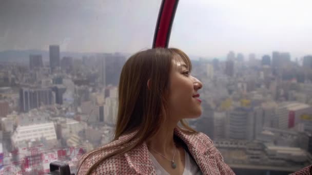 Glimlachende vrouw in reuzenrad hoog boven Osaka City, 4k — Stockvideo