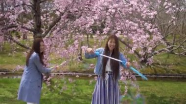 Bahar aylarında kiraz çiçeği parkında kabarcıklar ile oynayan Japon kadınlar, 4k