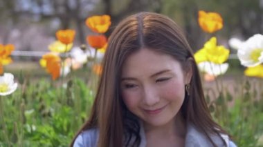 Bahar aylarında bir lale bahçesinin önünde gülümseyen Japon kadınların güzel portresi, 4k
