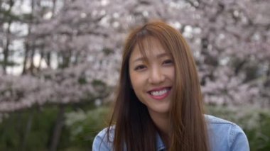 Cherry Blossom Seaon sırasında gülümseyen çekici Japon kadının portresi, 4k